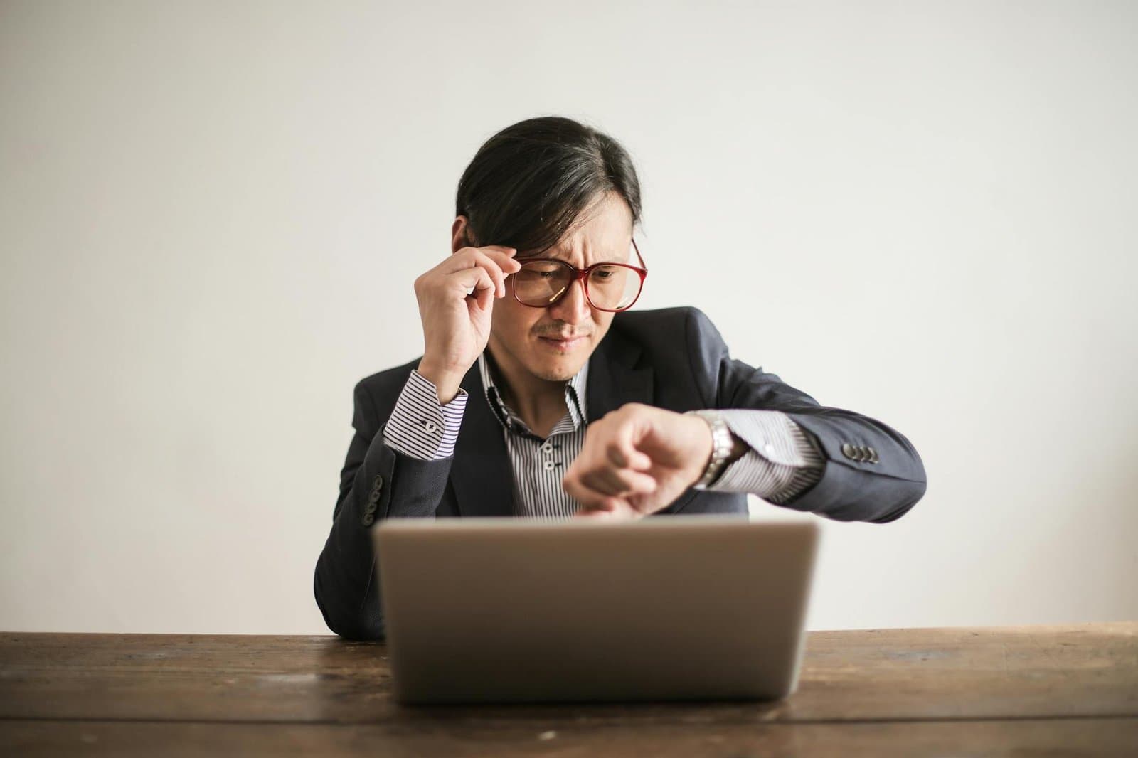 confused businessman checking time on wristwatch