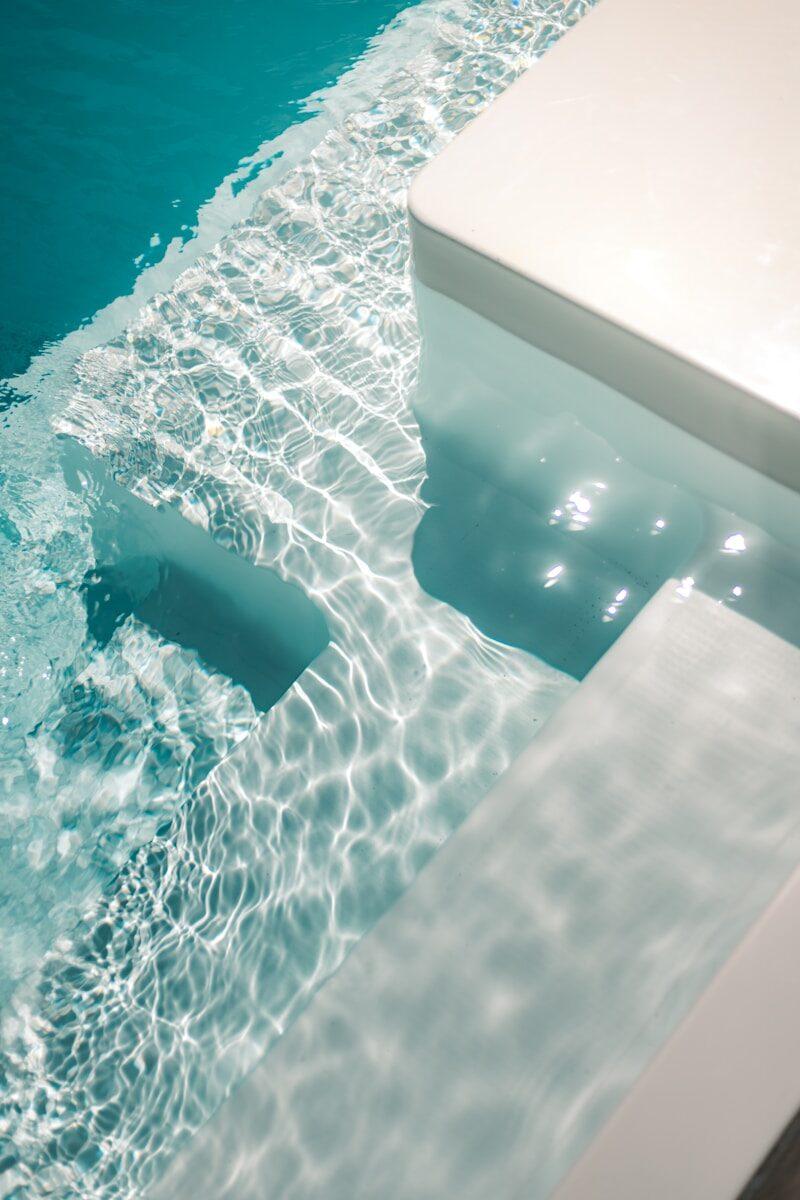 a pool with clear blue water and a white bench