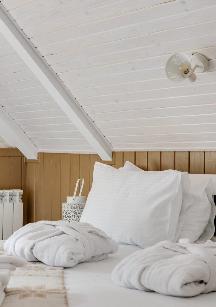 dressing gowns folded on a bed with white sheets in a short-term rentals