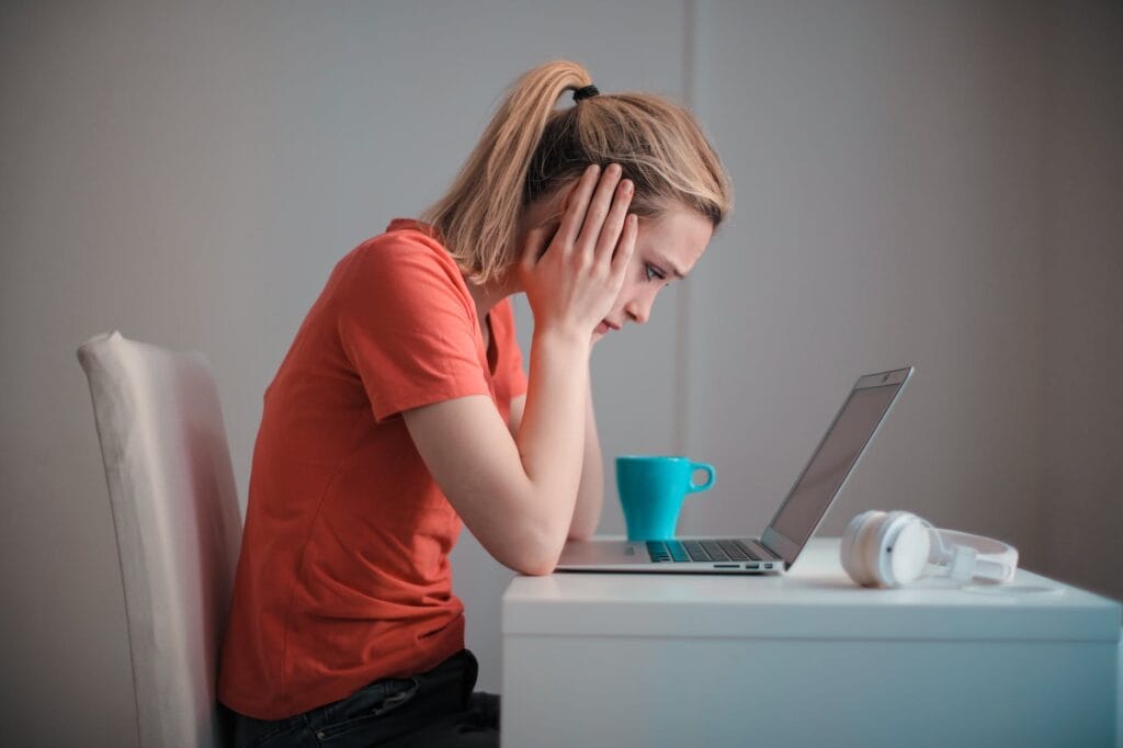 young troubled woman using laptop at home the Pros and Cons of Investing in Negative Cash Flow Properties
